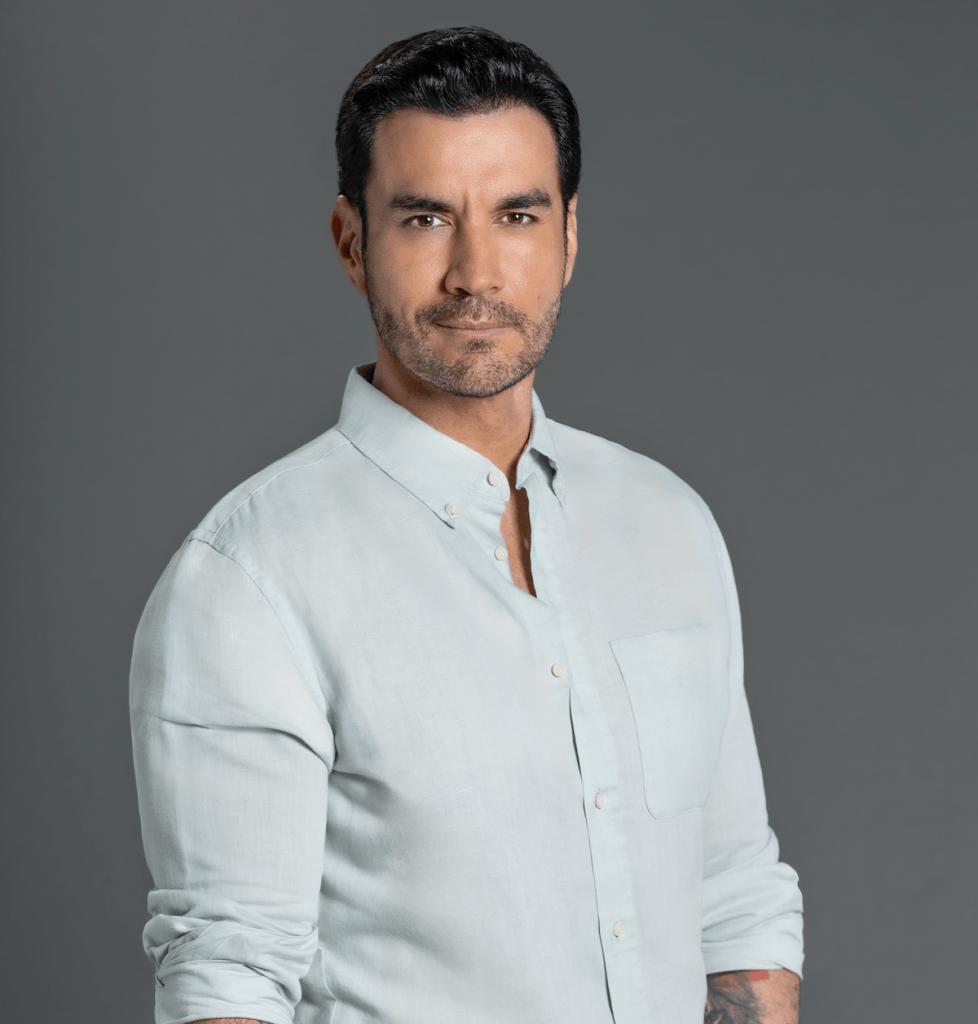 Retrato de Andrés Palacios, actor chileno, luciendo una camisa clara y posando frente a un fondo gris.
