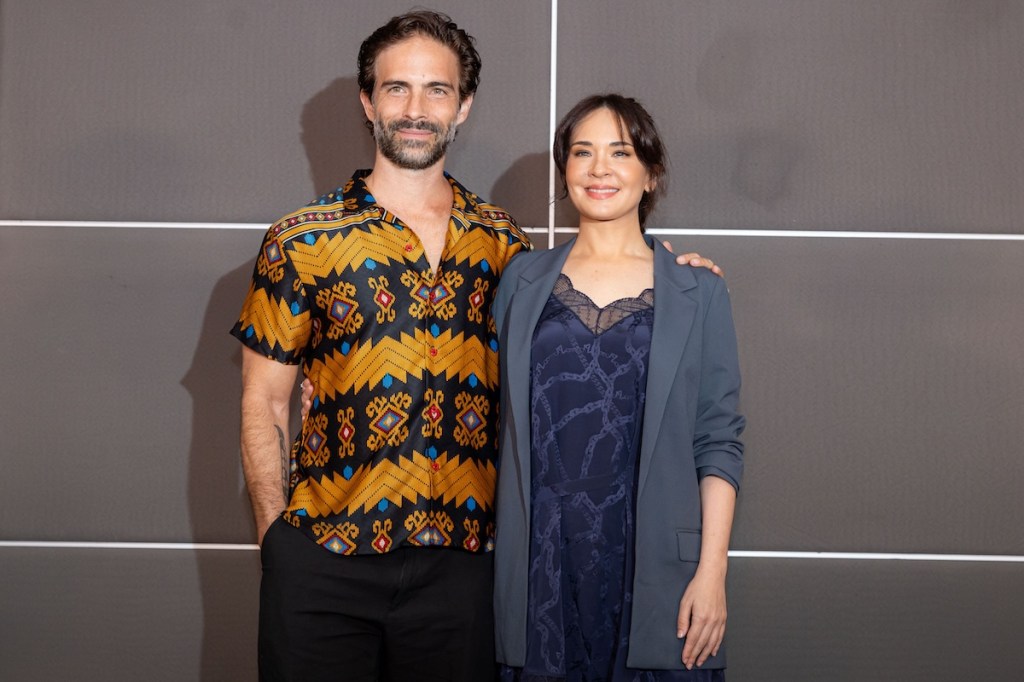 Adriana Louvier y un co-protagonista posando juntos sonrientes durante la presentación de la telenovela 'Hermanas, un amor compartido'.