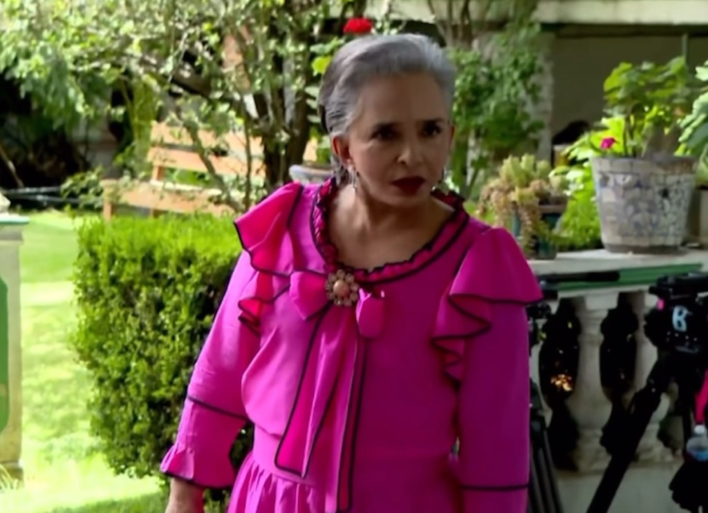 La actriz Ana Martín en el set de la telenovela Amanecer, vistiendo un vestido rosa con detalles negros, durante su primer día de grabaciones.
