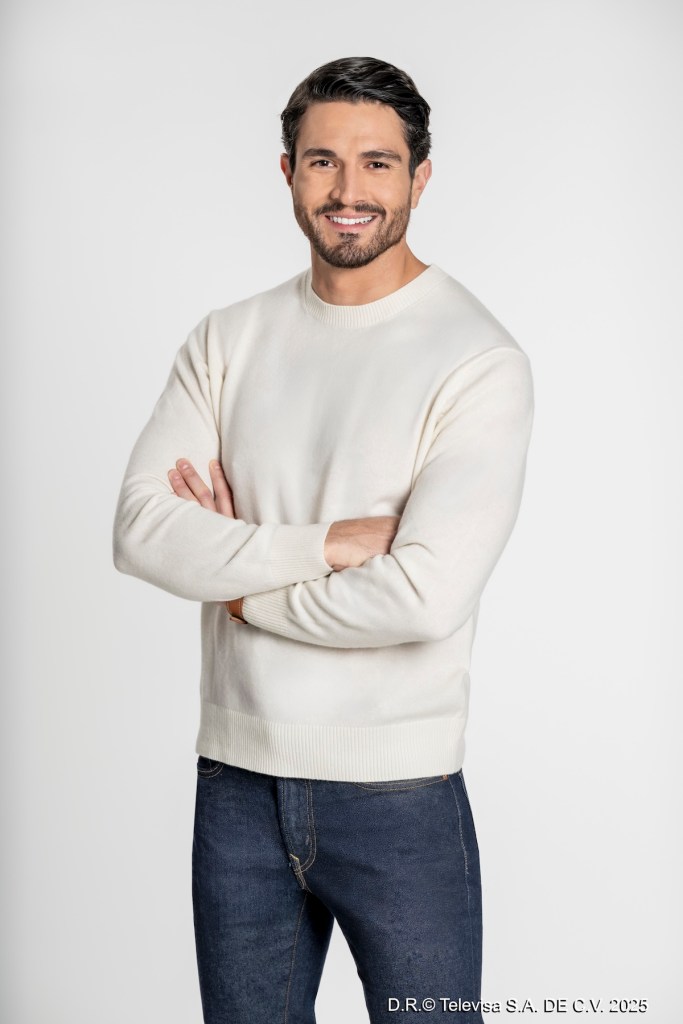 Retrato de Chris Pazcal sonriendo, con los brazos cruzados, vistiendo un suéter blanco y jeans oscuros, contra un fondo blanco.