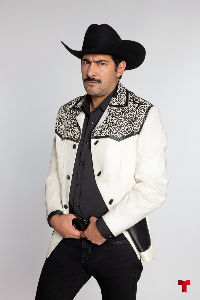 A man wearing a white jacket with black embroidery and a black cowboy hat, posing with a serious expression.