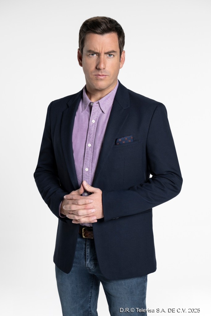 Retrato de un hombre con cabello corto y mirada seria, vestido con una chaqueta oscura sobre una camisa morada. Se muestra con las manos entrelazadas frente a él sobre un fondo blanco.