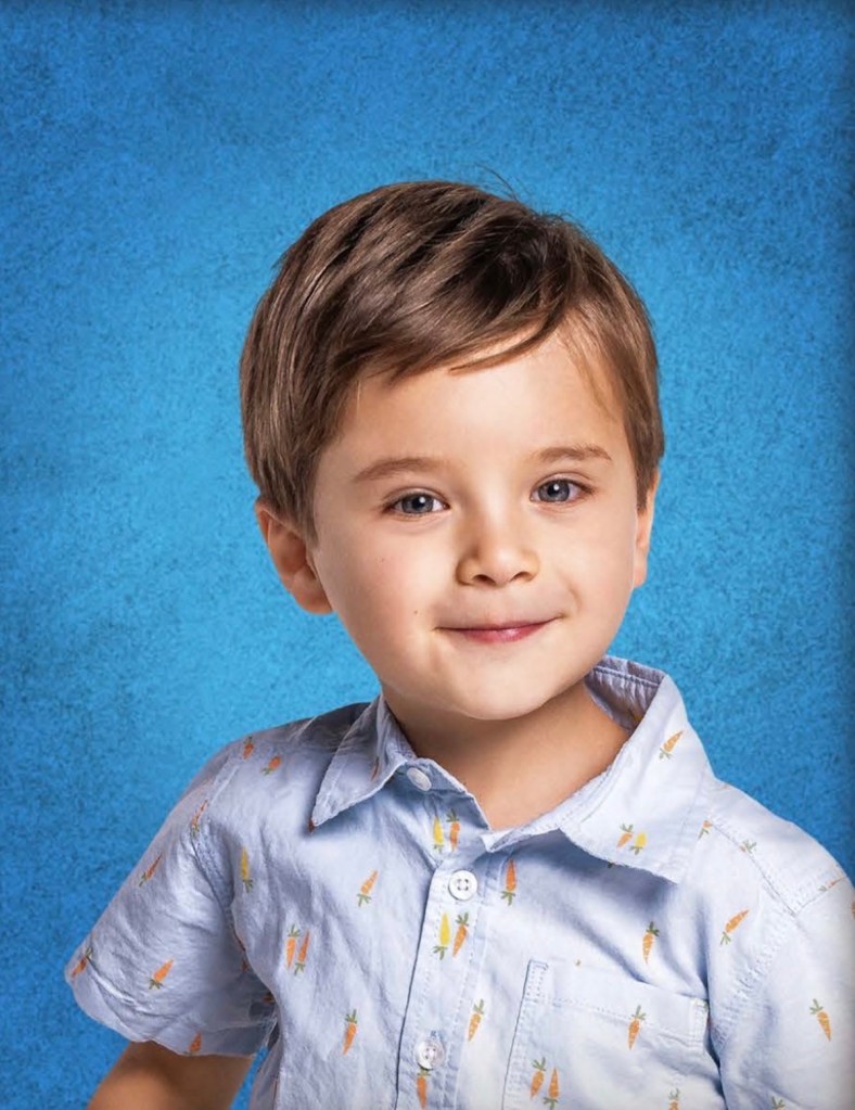 Retrato de un niño pequeño con cabello corto y castaño, usando una camisa azul clara con estampado de zanahorias, sonriendo frente a un fondo azul.
