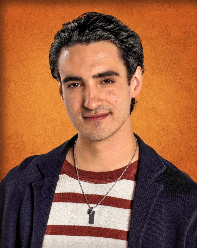 Retrato de un joven con cabello oscuro y lacio, vistiendo una camiseta de rayas rojas y blancas, acompañado de una chaqueta oscura. El fondo es de color naranja.