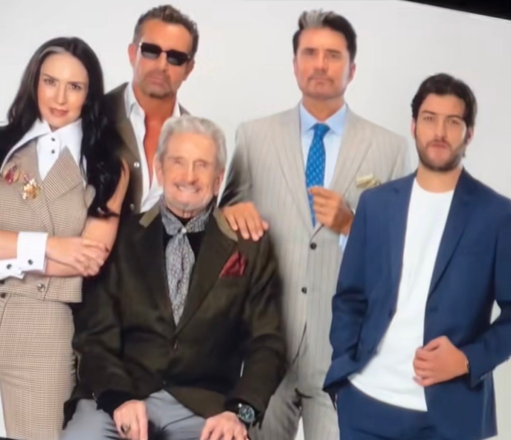 Grupo de actores posando para una sesión de fotos, con un fondo blanco. Se pueden ver cinco personas, algunas con trajes formales, sonriendo y mostrando diferentes poses.