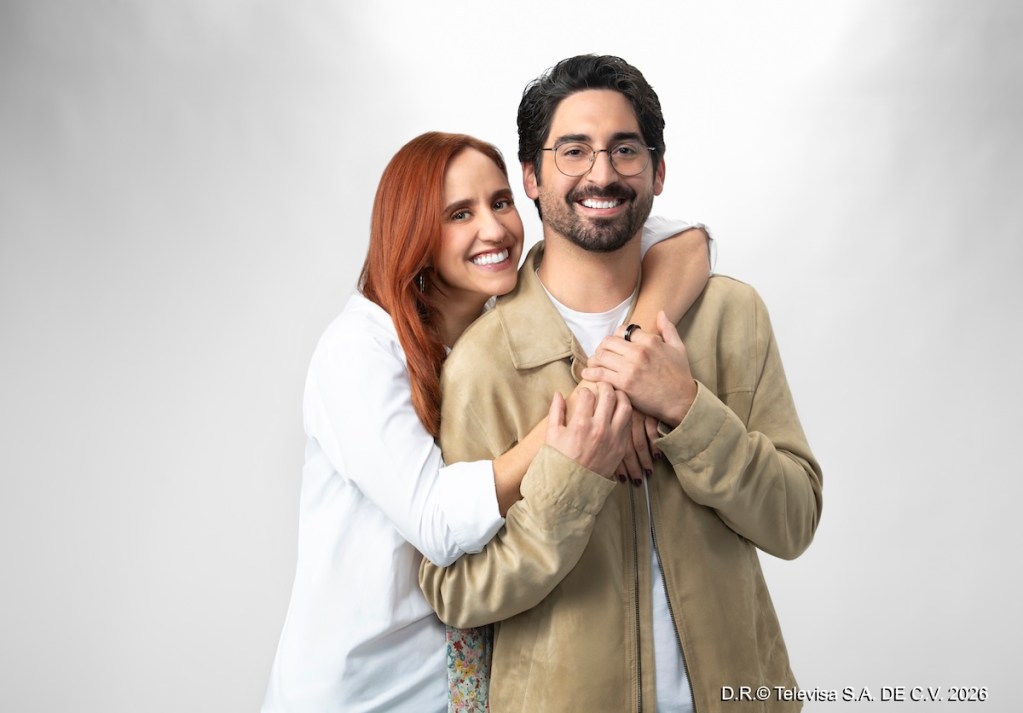 Pareja sonriente abrazándose, con fondo neutro.
