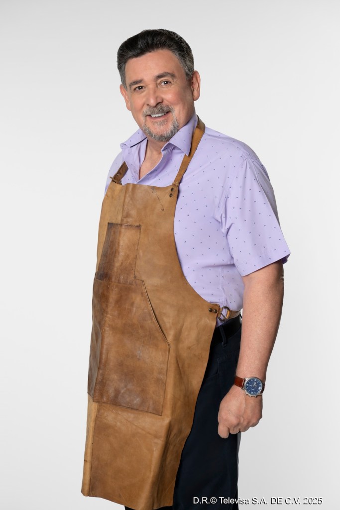 Hombre sonriente vestido con una camisa morada y un delantal de cuero, en un fondo blanco.